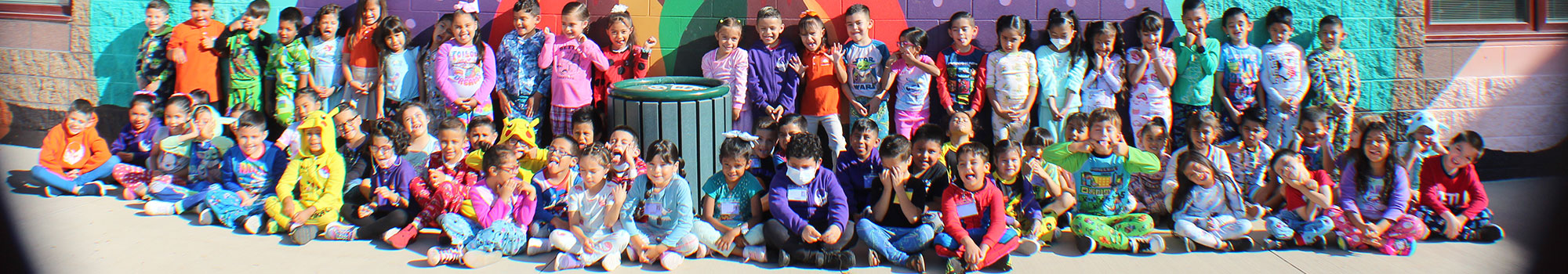 Big group of students posing in front of a mural