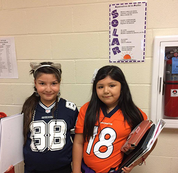 Two Salida del Sol school girls in front of a SOLAR poster